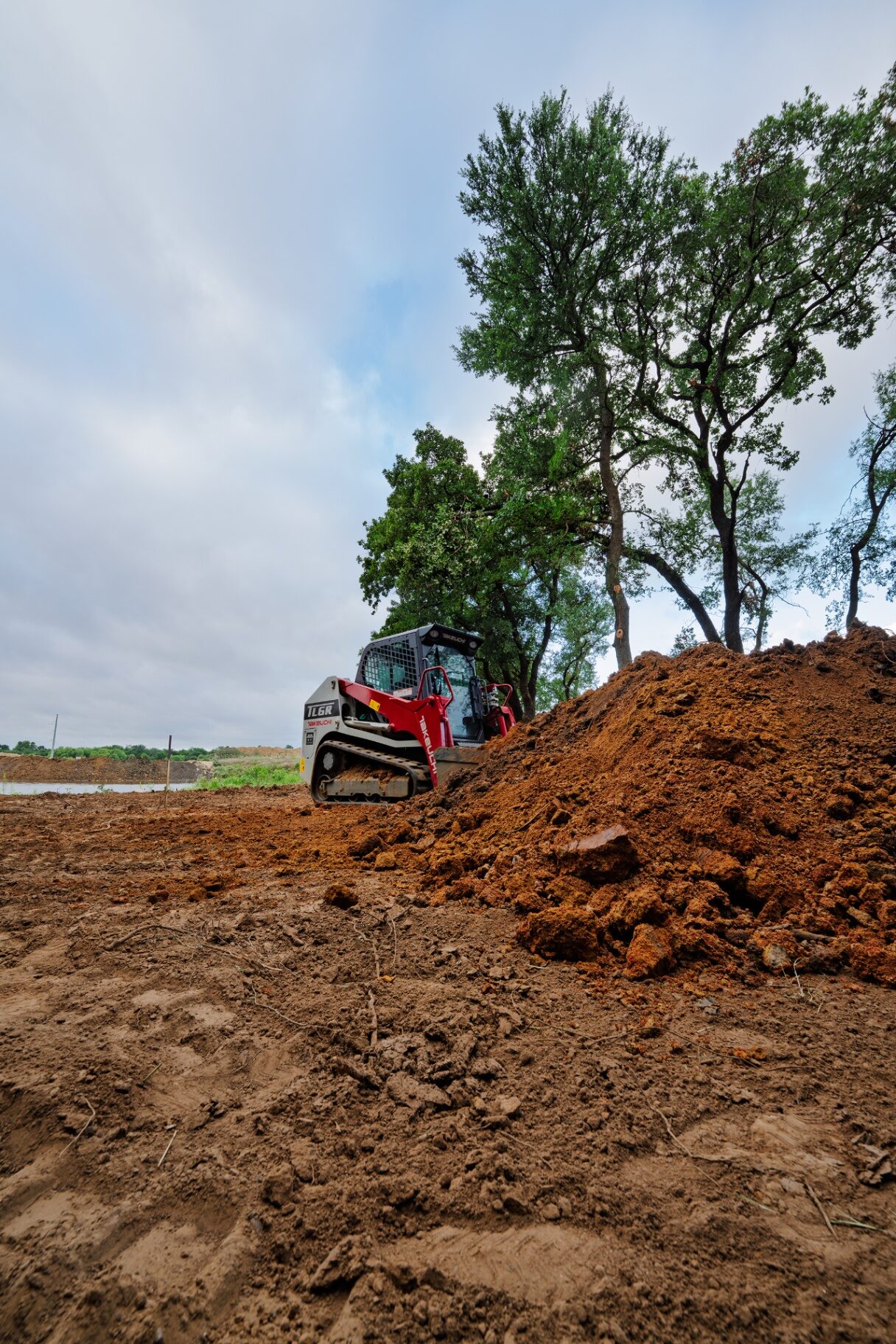 Skid steer moving a large dirt mound
